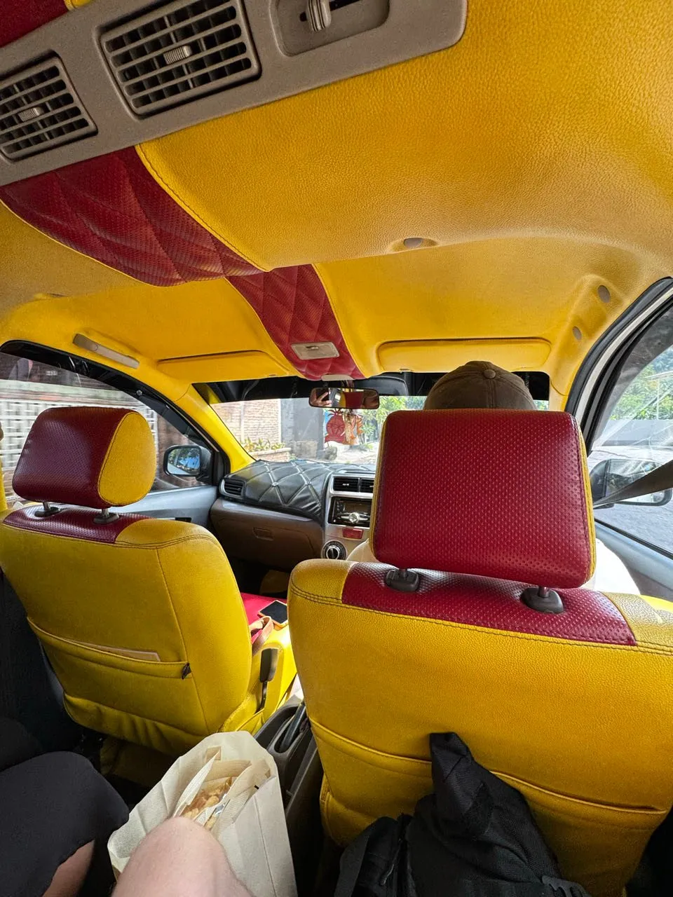 Im gelben Auto: Sitze und Dachhimmel in Gelb mit roten, gesteppten Einsätzen, unten links eine offene Papiertüte