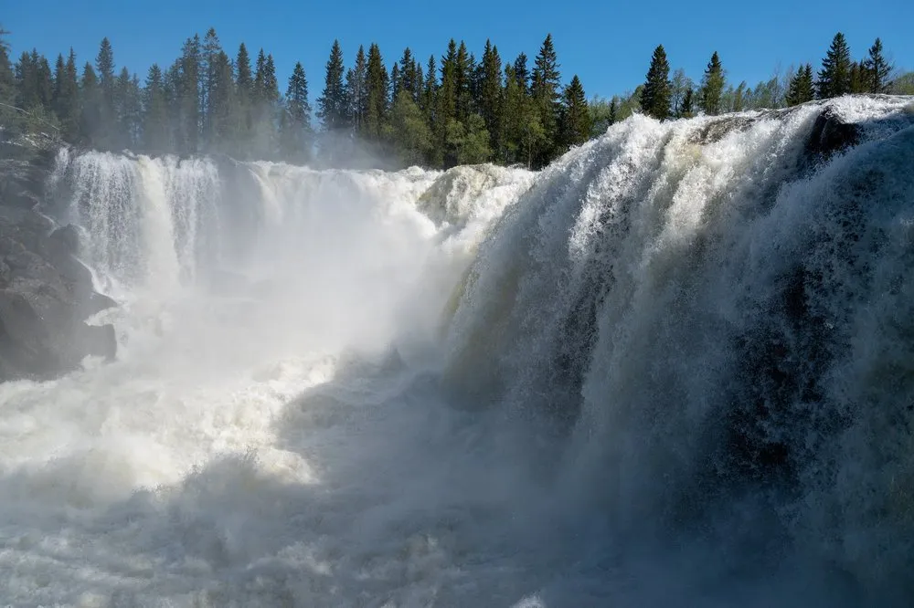 Masses of white water and spray at Ristafallet under a blue sky