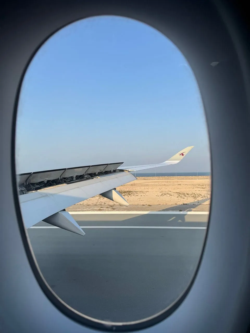 Landung in Doha, Blick auf die Piste und sandfarbenes flaches Land, am Horizont das Meer