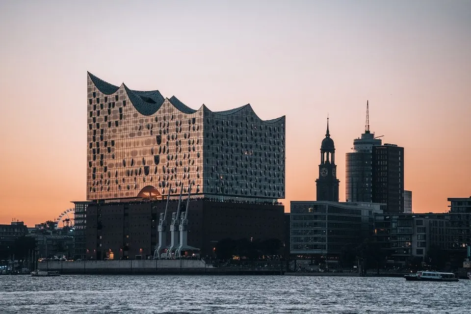 Elbphilharmonie und Michel als Silhouette vor dem Abendhimmel über dem Wasser in Hamburg