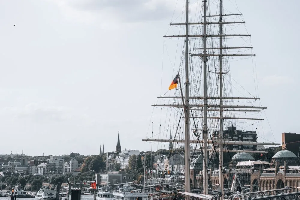 A tall ship moored in Hamburg harbour under a cloudy sky