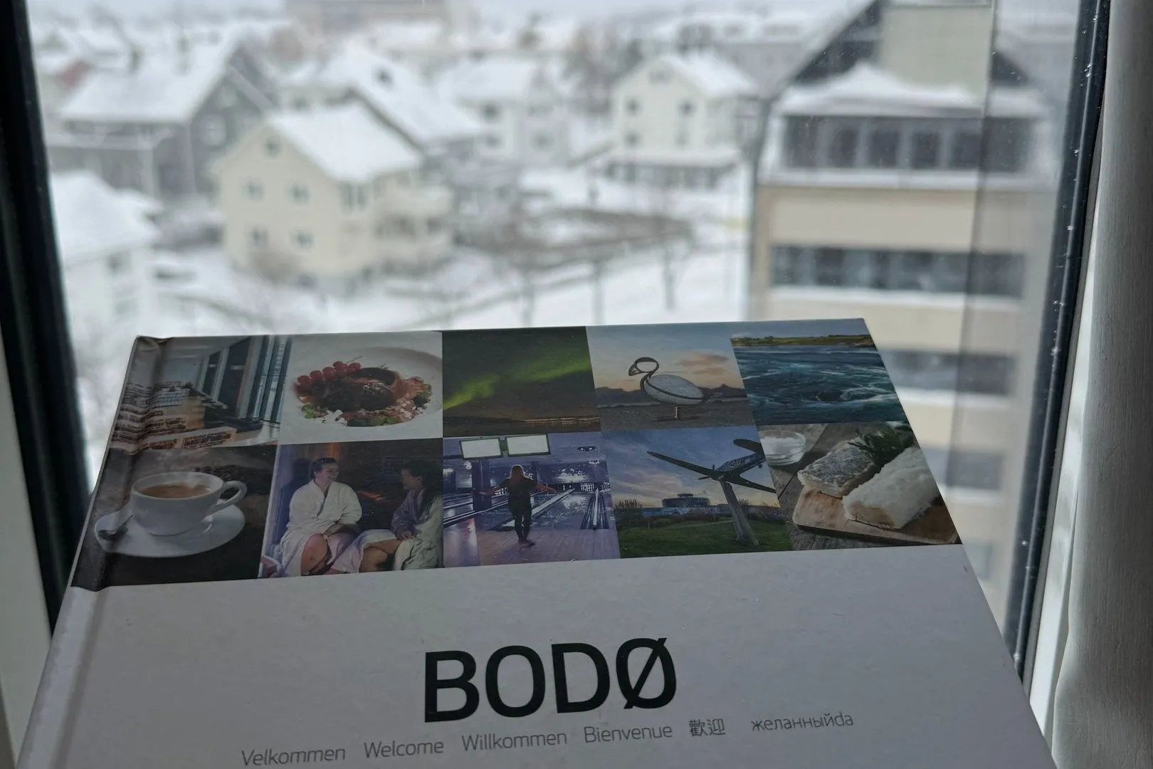A Bodø brochure on the windowsill, the snow-covered town outside