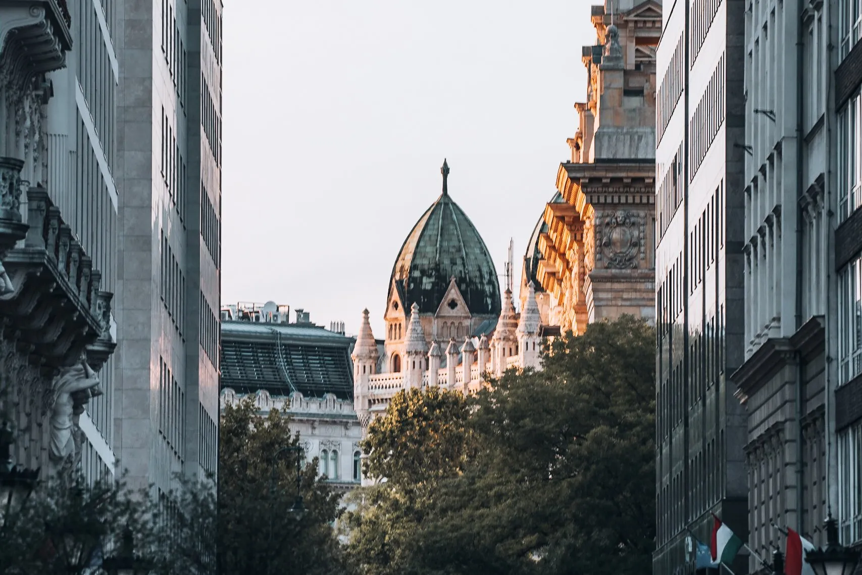 View between buildings onto a building with a green dome and pale turrets in the warm light