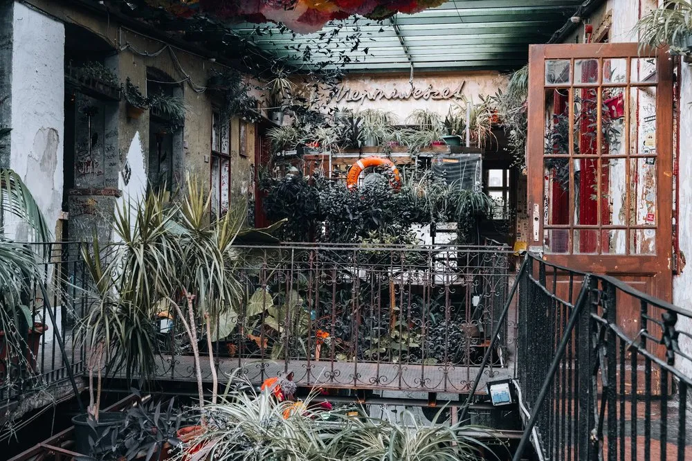 The planted courtyard of the ruin bar with weathered walls, an iron railing and an orange lifebuoy