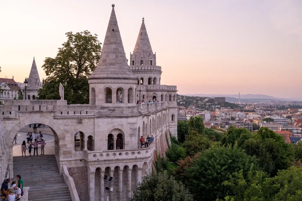 Die spitzen Türme der Fisherman's Bastion im rosa Abendlicht, rechts die Dächer der Stadt