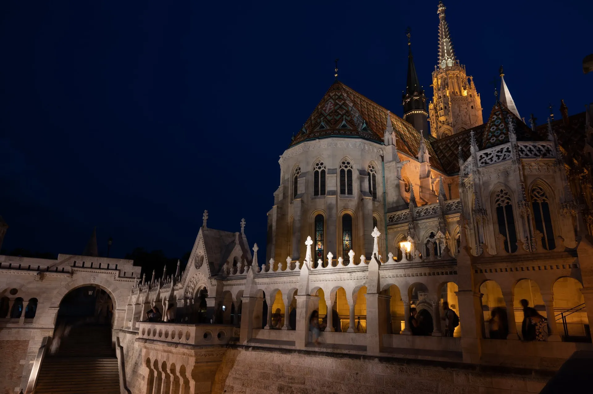 The arcades of Fisherman's Bastion in the evening light, behind them the lit-up church, at the bottom left a staircase