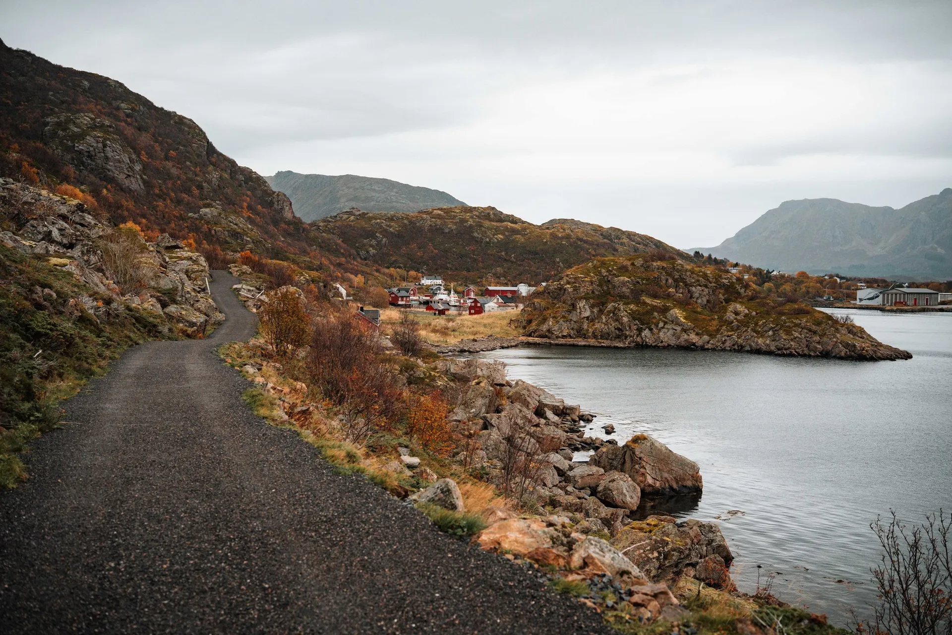 Ein Kiesweg führt der Bucht von Straumsjøen entlang, unten rote Häuser auf einer kleinen Halbinsel