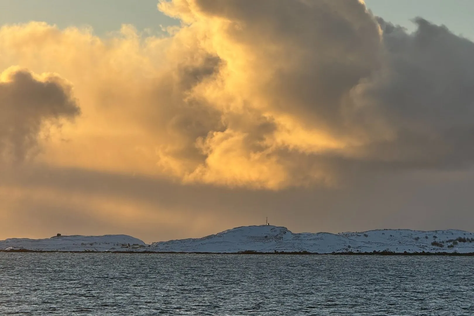 A cloud bank lit gold above the sea, seen from the ferry