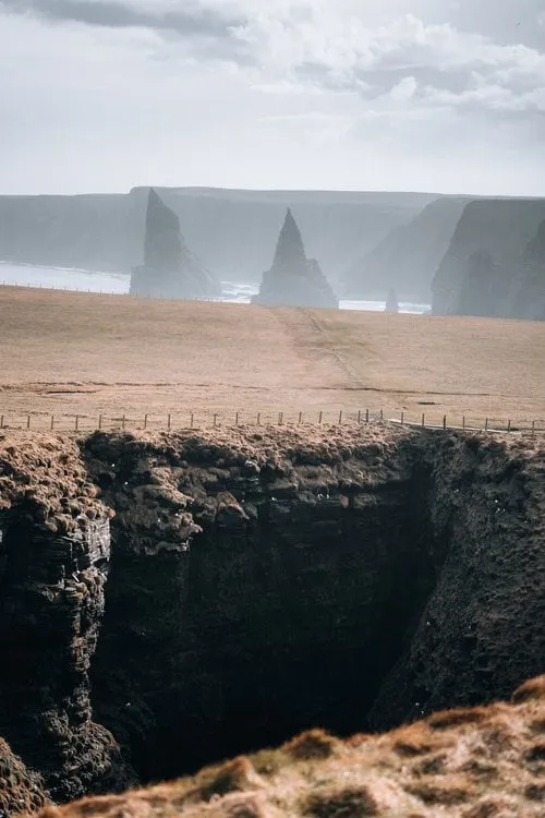 Blick über die Wiesen der Klippenkante auf die Nadeln von Duncansby