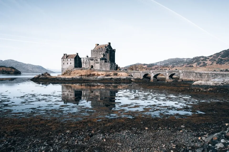 Eilean Donan Castle on its island, mirrored in the shallow water of the loch