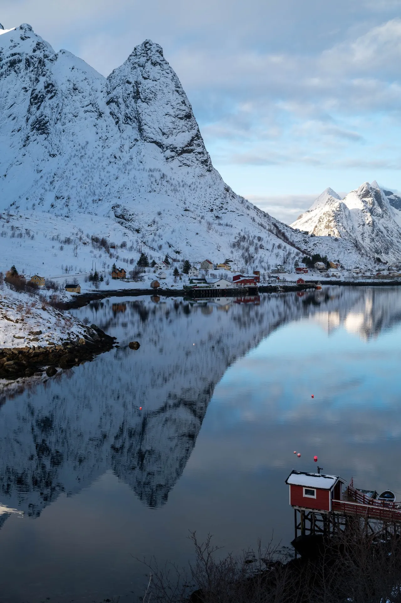 Snow-covered peaks mirrored in the calm fjord at Sakrisøy