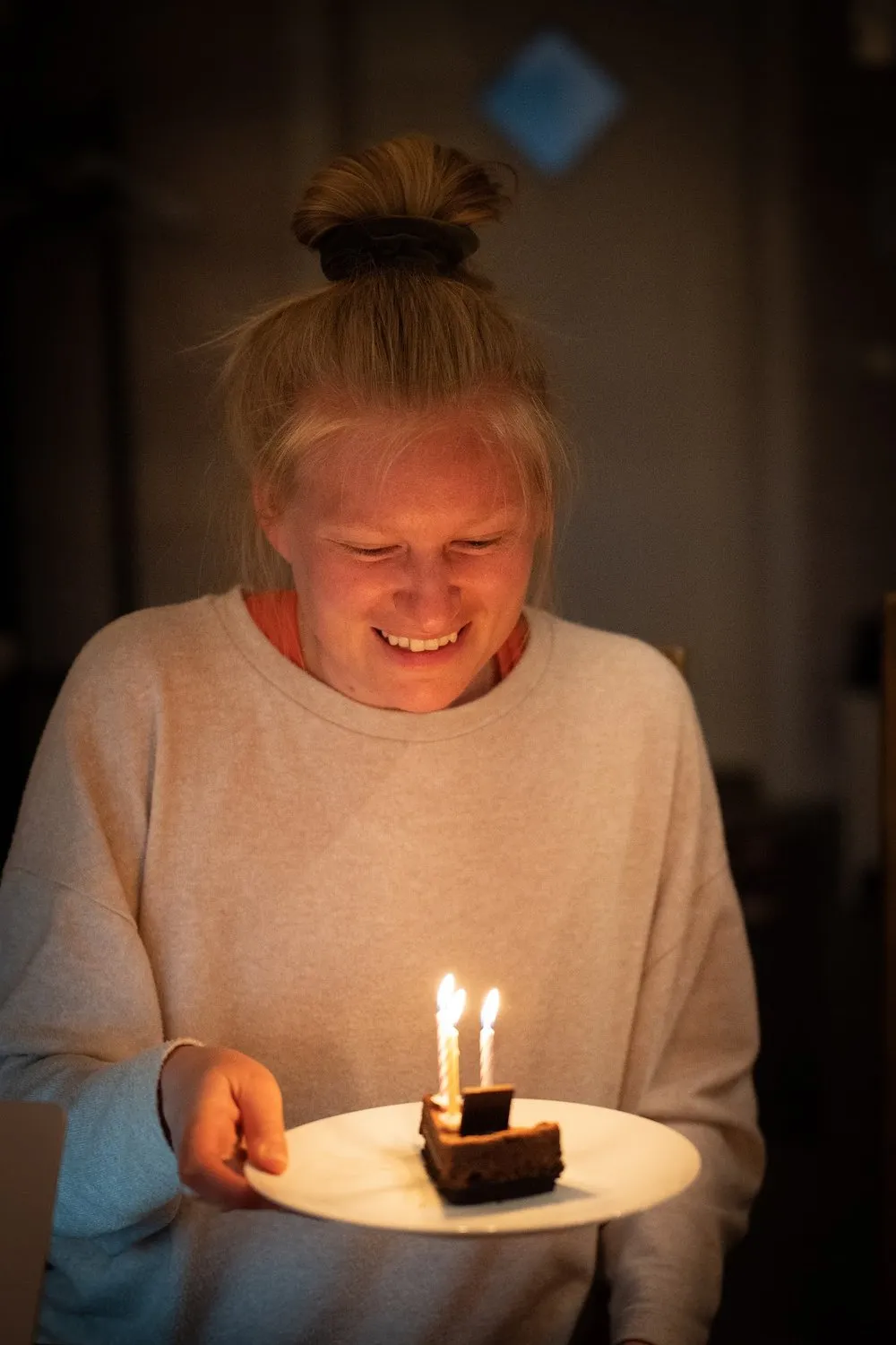 Annina smiles down at a slice of chocolate cake with burning candles