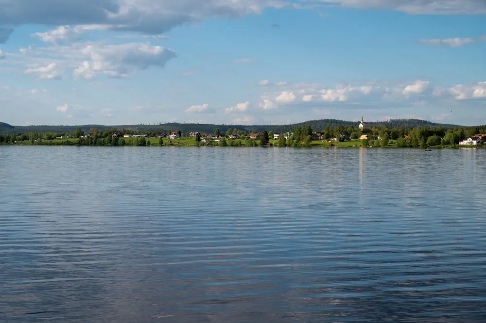View across the lake to a village with a light-coloured church tower on the opposite shore