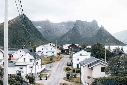 The village street of Husøy between white houses, sharp peaks behind