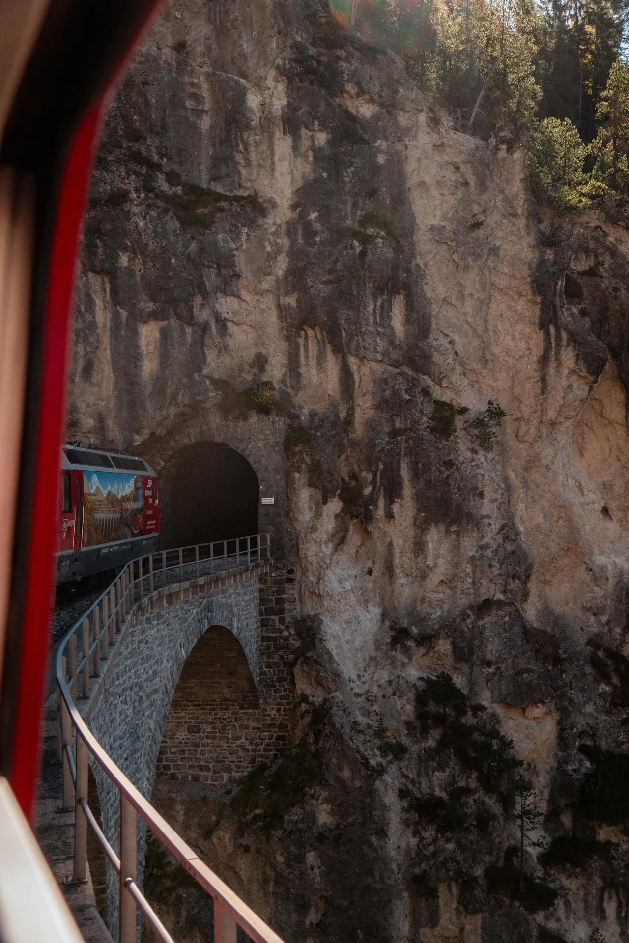 Vorne fährt die Lok mit der Bemalung zur Weltrekord-Fahrt vom Landwasserviadukt in den Tunnel in der Felswand