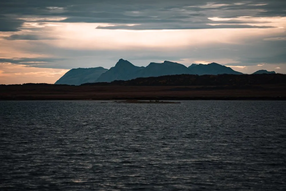 Dark mountain silhouettes above the water in the morning light, on the drive from Nøss to Andenes
