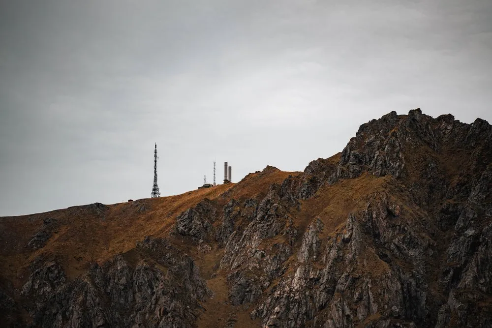 Antenna masts on a rocky ridge above Bleik under a grey sky