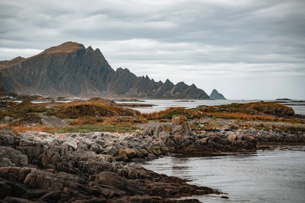 Rocks and water by the lighthouse in Andenes, the jagged mountains of Andøya behind