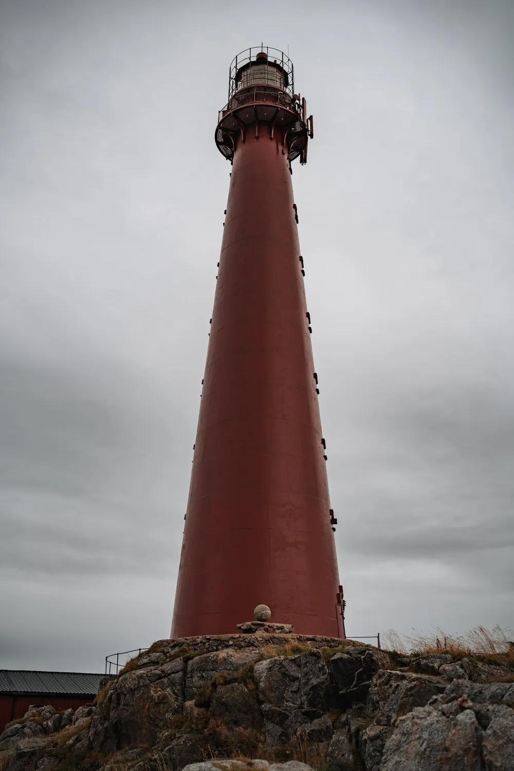 The red lighthouse of Andenes from below against the grey sky