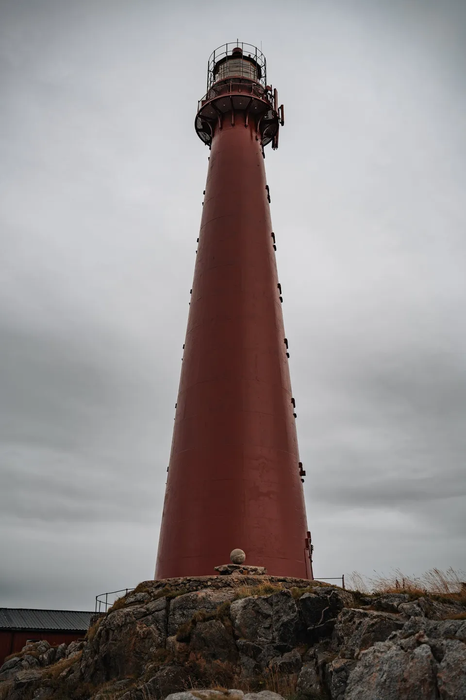 Der rote Leuchtturm von Andenes von unten gegen den grauen Himmel