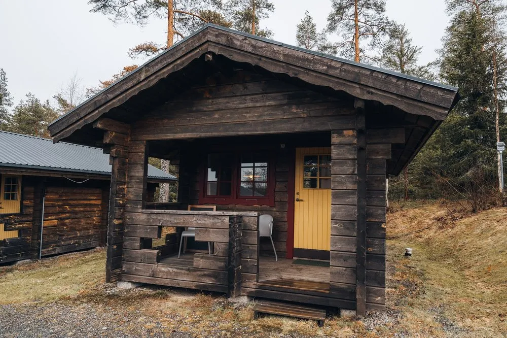Eine Holzhütte mit gelber Tür und kleiner Veranda zwischen Kiefern