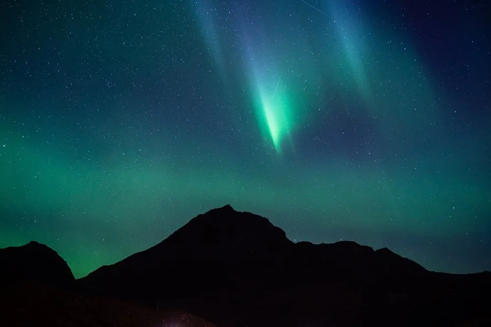 A bright green ray above a dark mountain peak