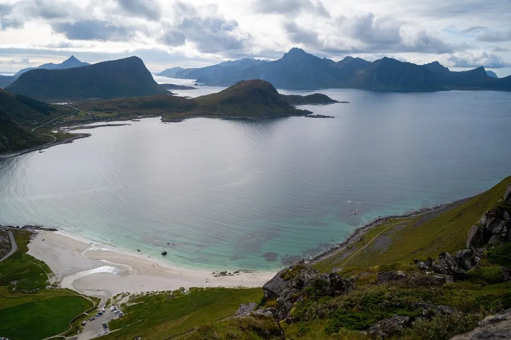 The bay with turquoise water and a pale sandy beach, the car park at the bottom edge