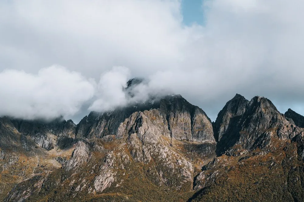 Rocky mountain peaks in warm autumn light, the tips hidden in clouds