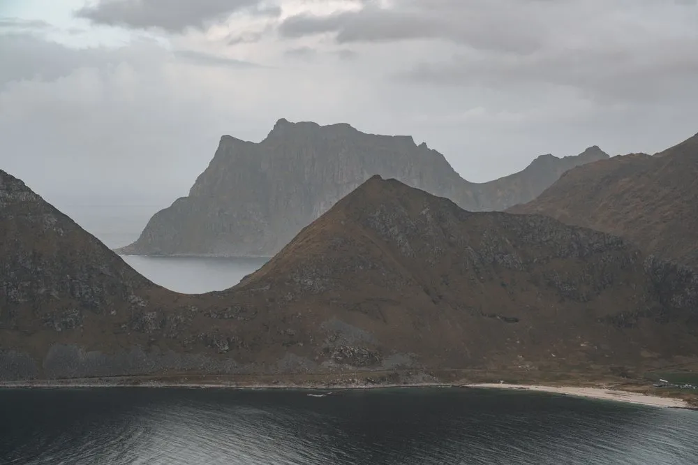 Ein Tafelberg hinter einem rotbraunen Hügel und einem schmalen Strand, gesehen vom Offersøykammen