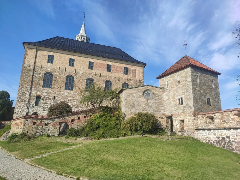 Die Festung Akershus mit hellen Steinmauern, einem Turm mit rotem Ziegeldach und einem langen Bau mit schwarzem Dach