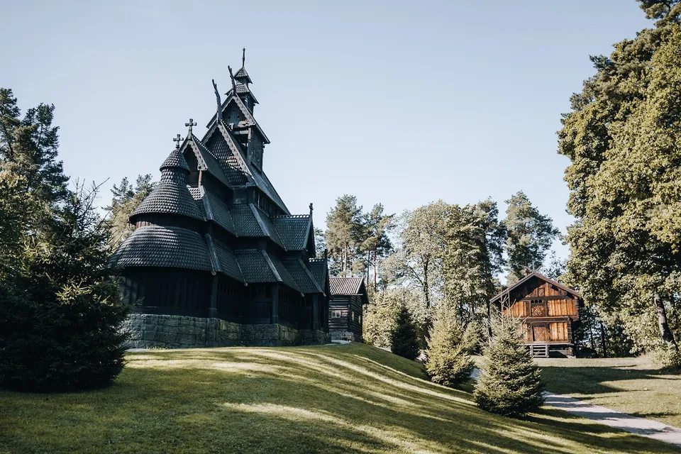 Die Stabkirche Gol aus dunklem Holz mit Schindeldächern und mehreren Türmchen auf einer Wiese