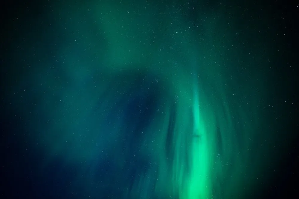 Green northern lights in veils across the whole sky, many stars in between