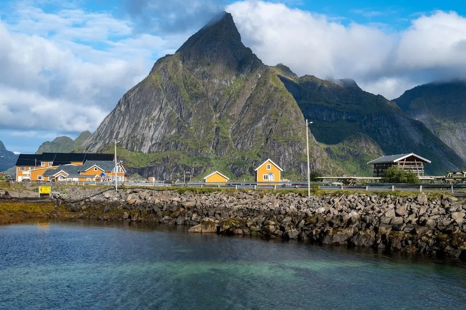 The yellow houses of Sakrisøy below Olstind above clear water