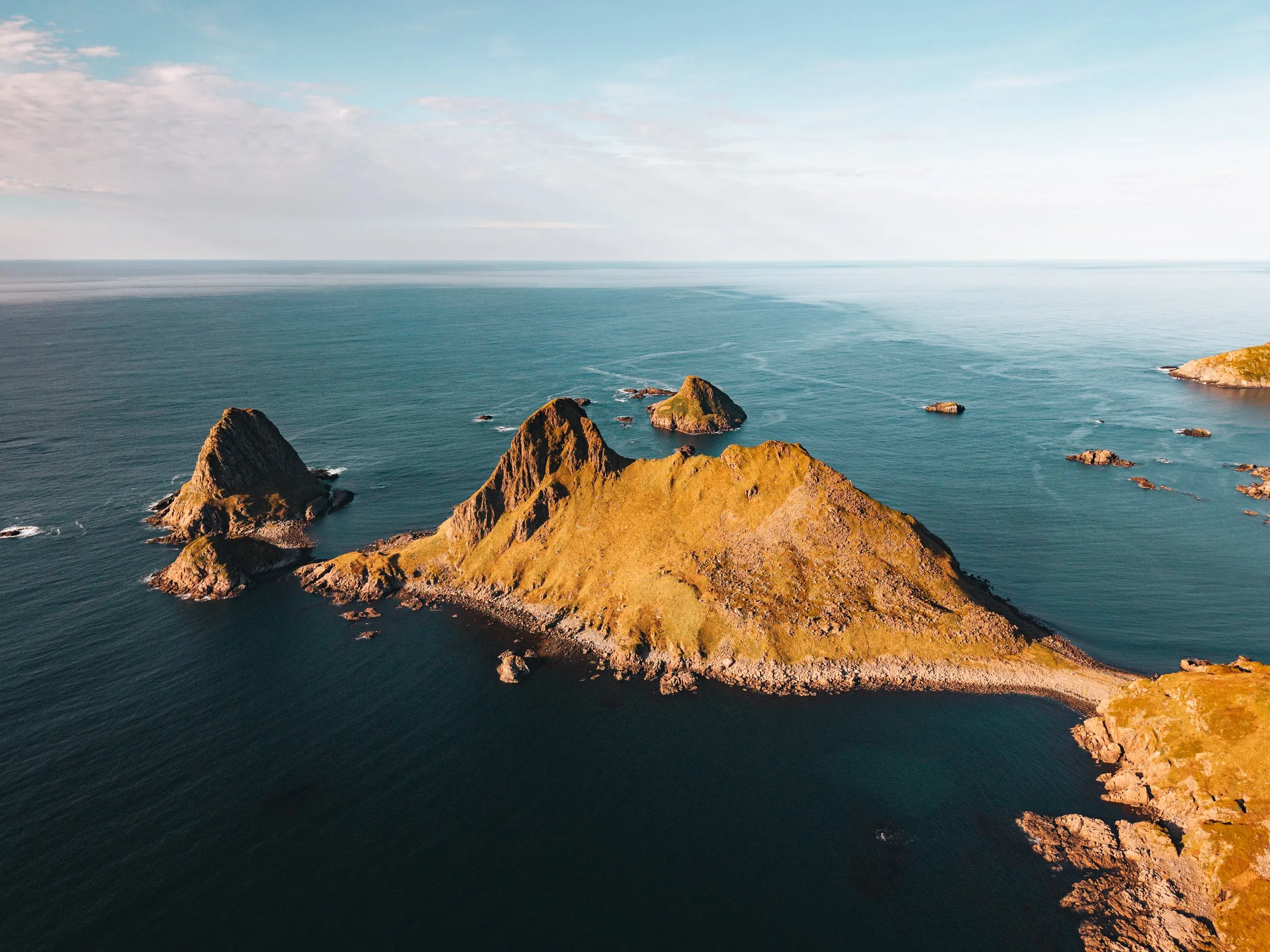 The rocky peninsula of Engenyken and small rocky islets in golden light, from the air above Bufjellet near Sandvika