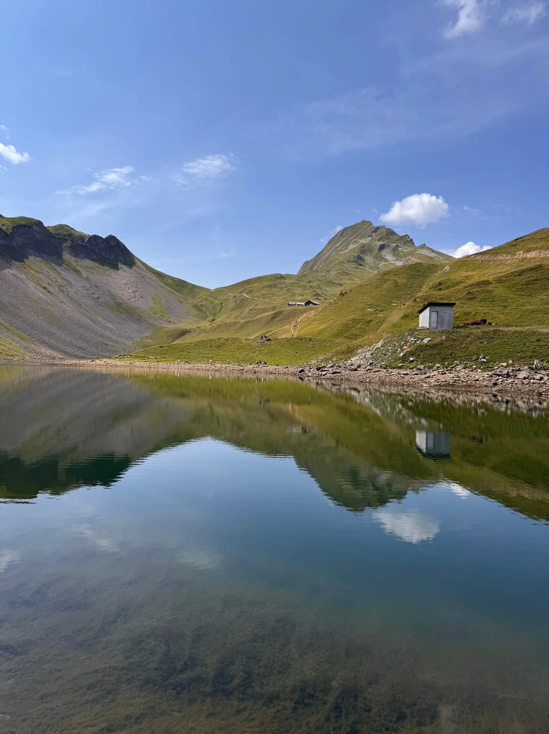 The Eisee mirroring mountains and clouds, a small hut on its shore