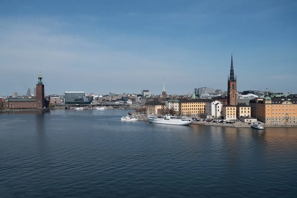 Ruhiges Wasser vor der Stockholmer Innenstadt, links das Stadhus mit seinem Turm, rechts Häuser und ein spitzer Kirchturm