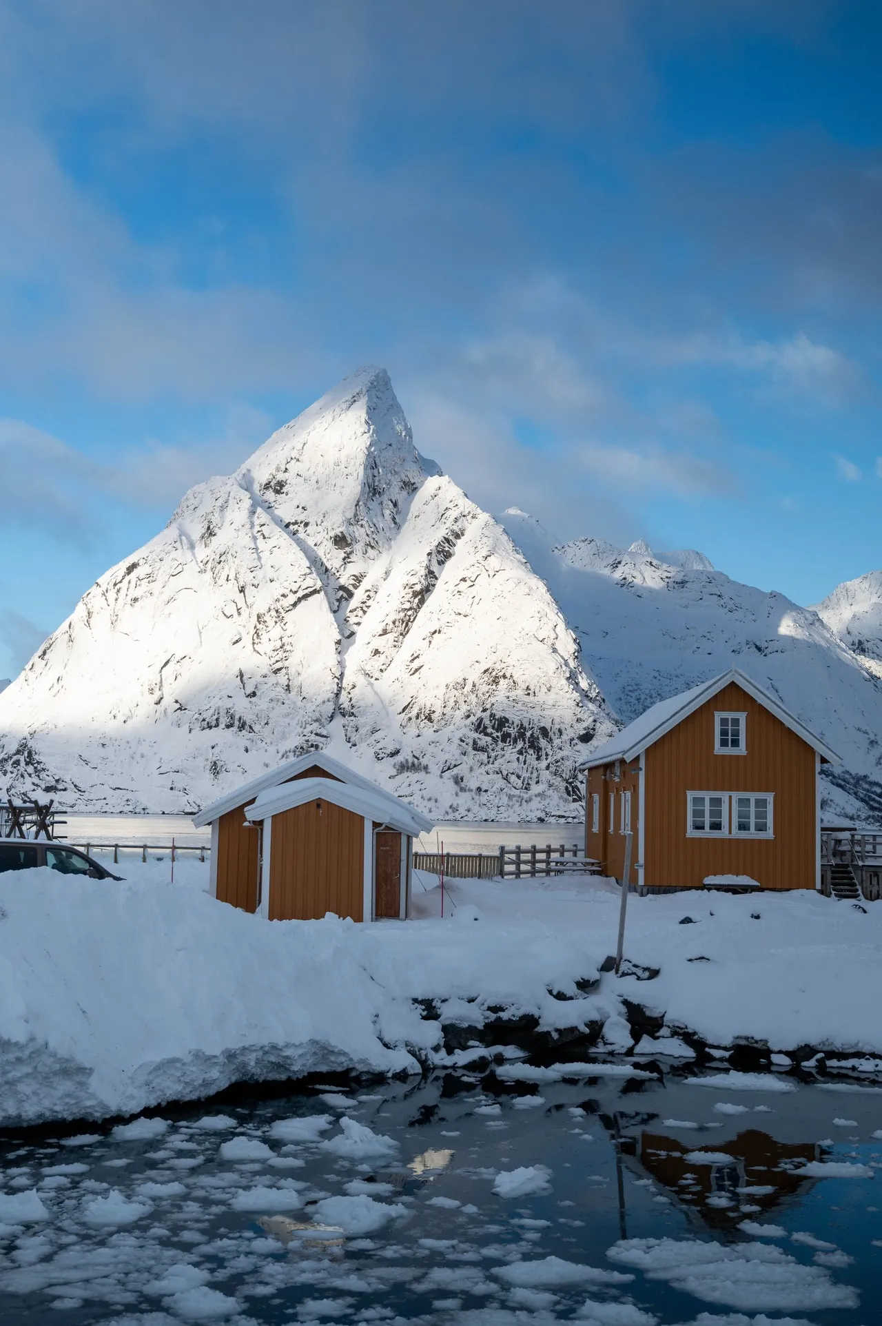 Two yellow houses below the pointed summit, drift ice in front