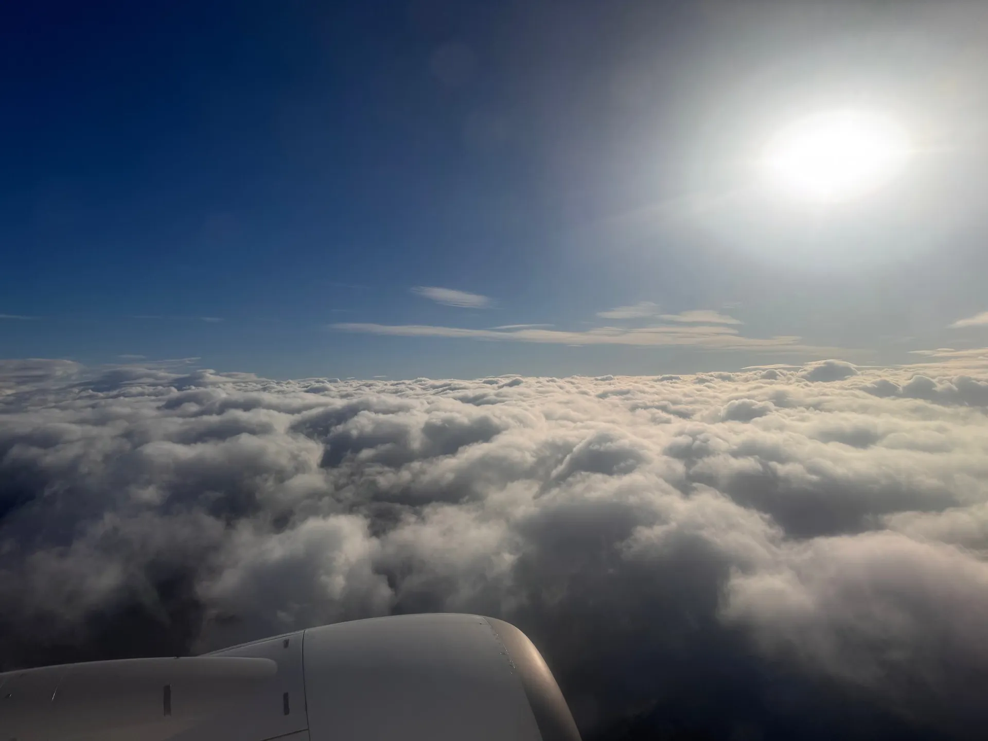 Über den Wolken nach dem Start in Evenes, die Sonne über der weissen Wolkendecke, unten das Triebwerk