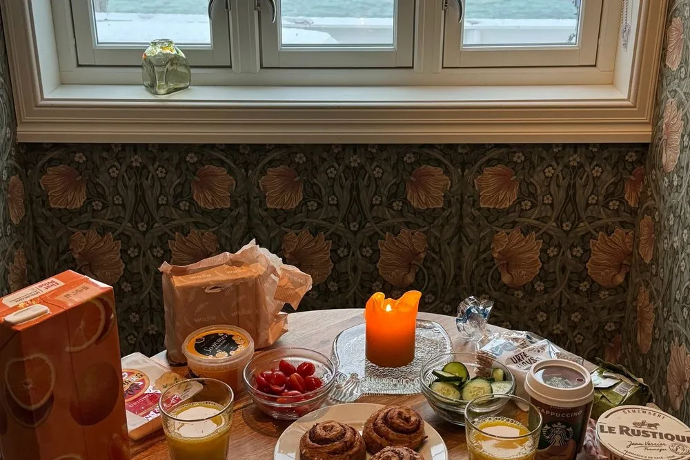 A breakfast table with cinnamon buns by the window, the fjord outside