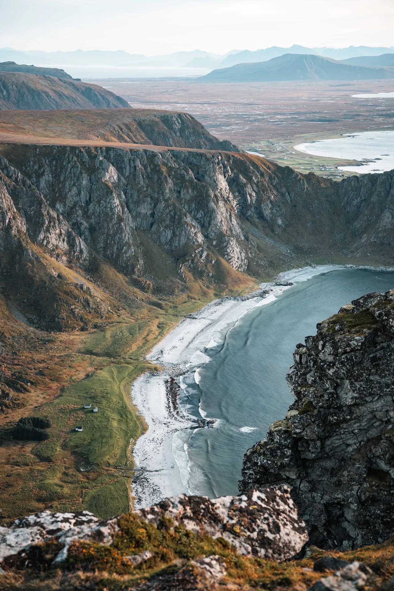 Tief unter steilen Felswänden liegt eine Bucht mit hellem Strand, vom Måtind aus