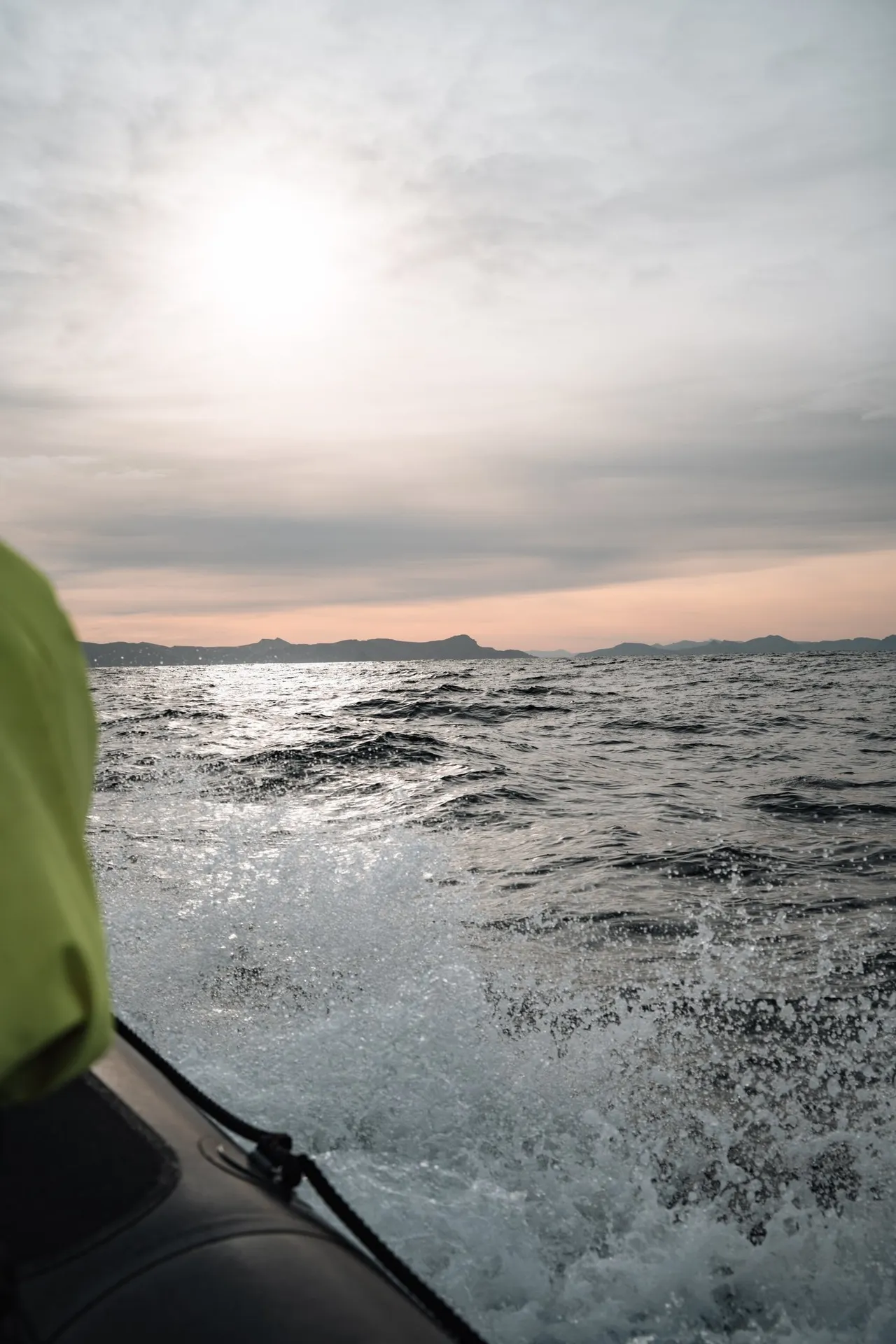 Gischt spritzt neben dem RIB-Boot auf, im Gegenlicht glitzert das Meer vor Andenes