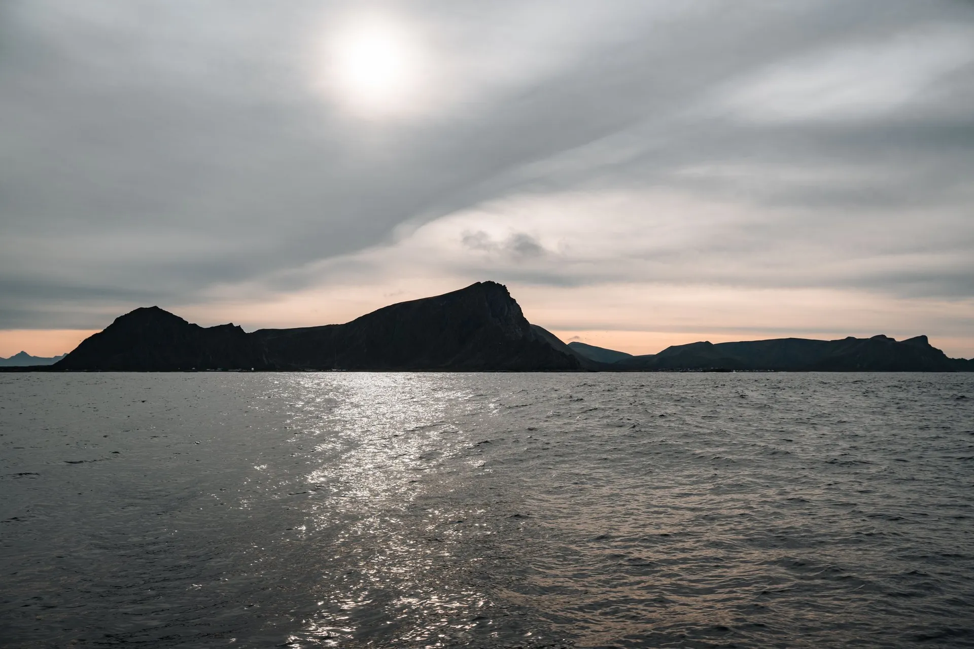 Eine dunkle Insel im Gegenlicht, die Sonne glitzert auf dem Meer, auf der Rückfahrt nach Andenes