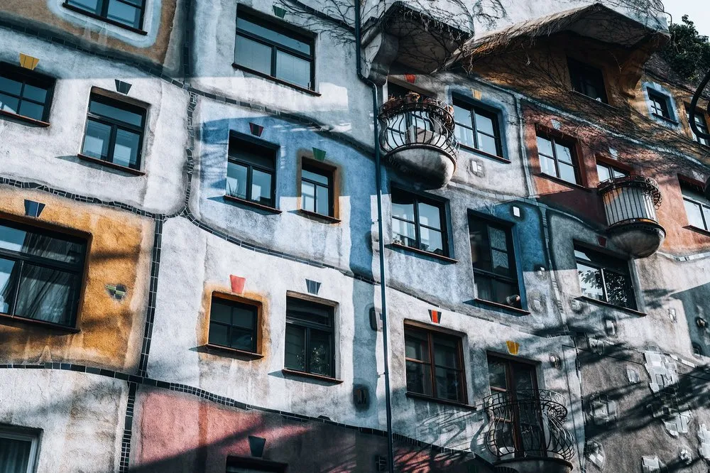 Colourful house façade with irregularly placed windows, coloured surfaces, round balconies and wavy dark lines