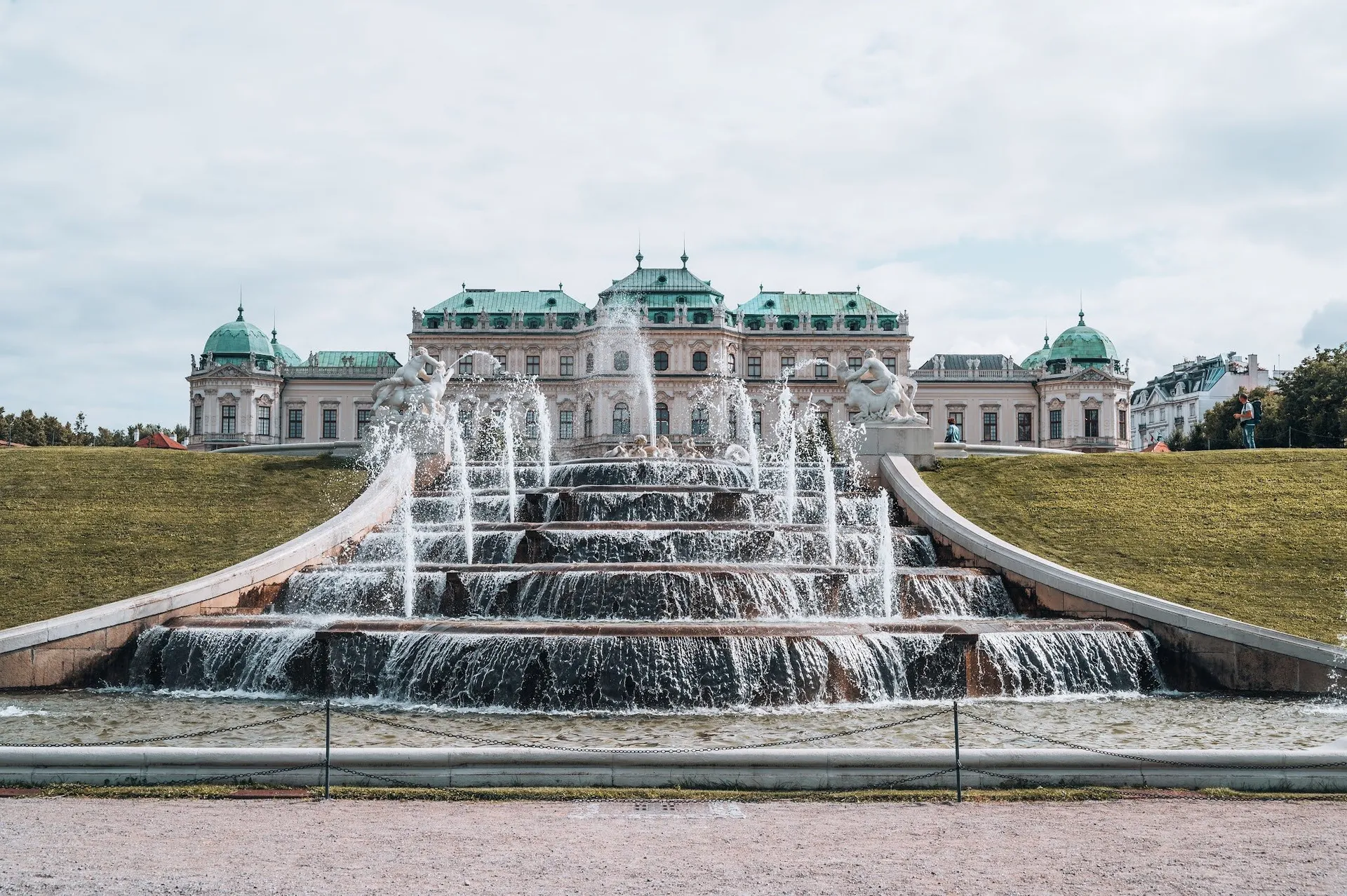 The cascade up close, the jets of water leaping between the steps, behind them the green roofs of the palace